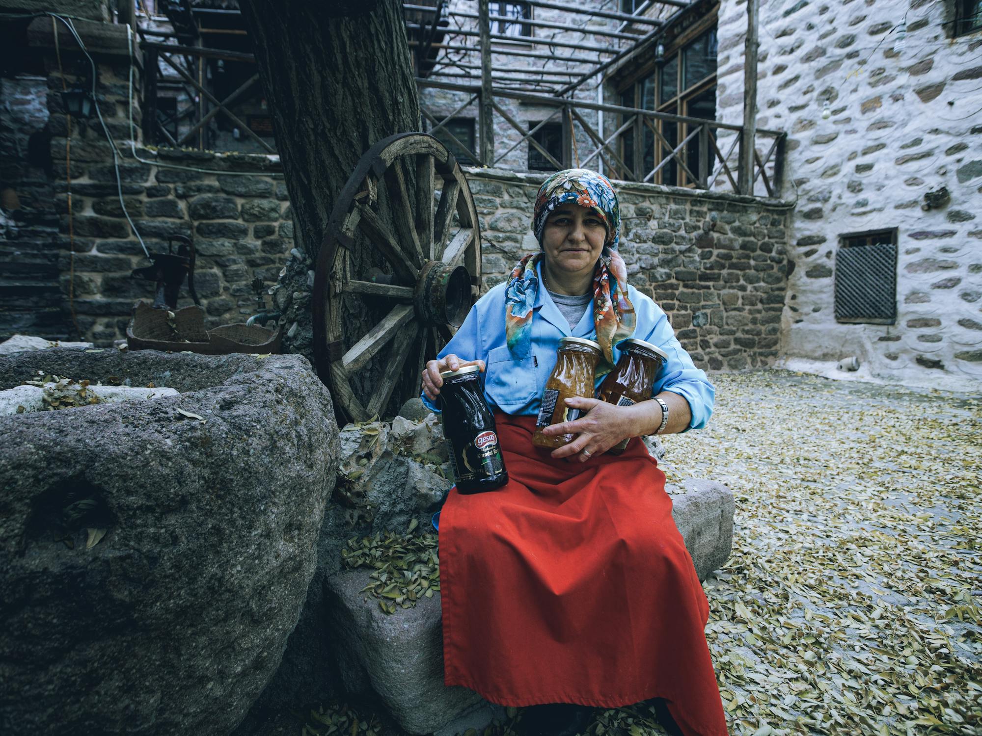 Mujer artesana en su pequeño negocio en un pueblo rural, trabajando con sus manos en una pieza tradicional, rodeada de materiales y herramientas que reflejan su historia y herencia cultural.